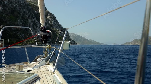 A view through the yacht's protective railings onto a sea bay surrounded by rocky shores
