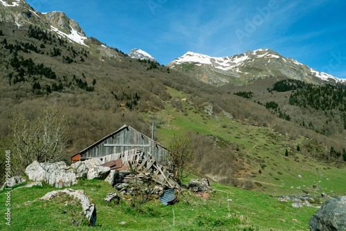 Rustic cabin nestled among mountains with snow-covered peaks and green meadows,Pyrenees, france