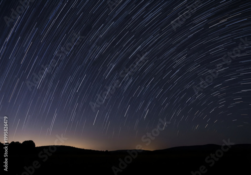 Long exposure star trails over silhouetted horizon at night