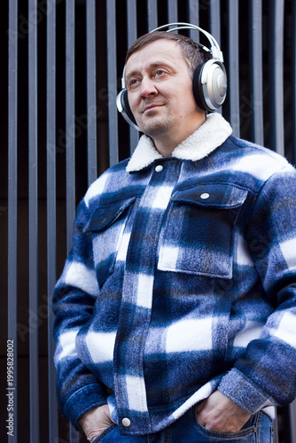 Sad pensive man with headphones against abstract wall background