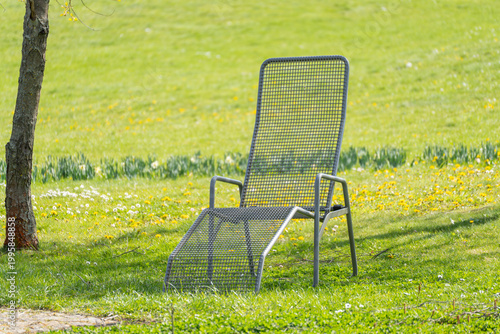 Canvas Print Metal chair rests on soft grass, bathed in sunlight
