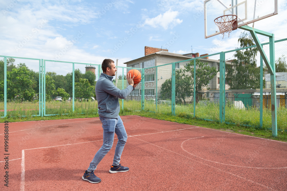 Fototapeta premium Man playing ball at the outdoor basketball court