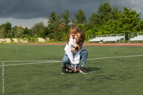 Woman teaching her daughter soccer ball at sport field