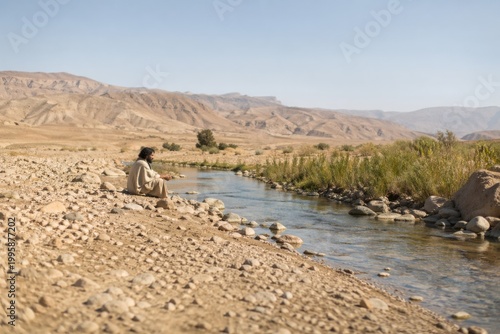 elijah sitting alone beside the brook cherith in a dry wilderness, a contemplative biblical scene of prophetic solitude, waiting and dependence under stark light and quiet desolation