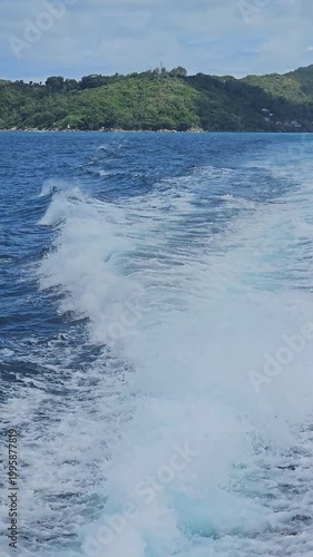 Boat wake on turquoise ocean near tropical island, travel and vacation concept, speed and freedom