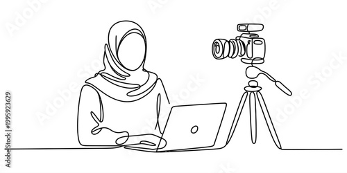 Woman wearing hijab filming video with laptop and camera