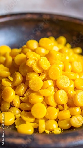 Pile of yellow circular candies in a dark bowl