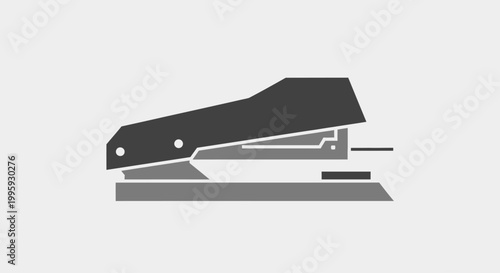 Black office stapler on desk surface.