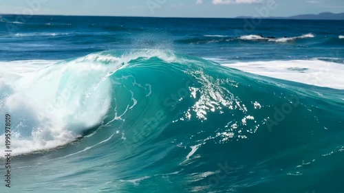 Turquoise ocean wave crashing in the bright blue sea on a sunny day