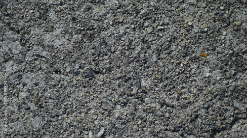 Detailed macro shot of weathered grey concrete pavement with small gravel aggregates