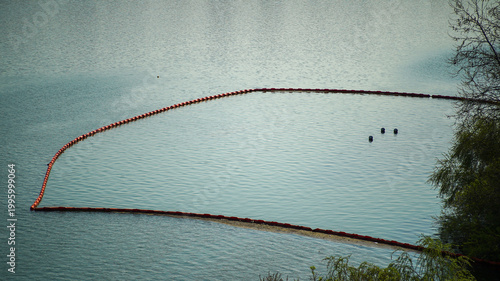 Orange safety buoys and silt curtain floating on the water surface to protect a construction site or environment