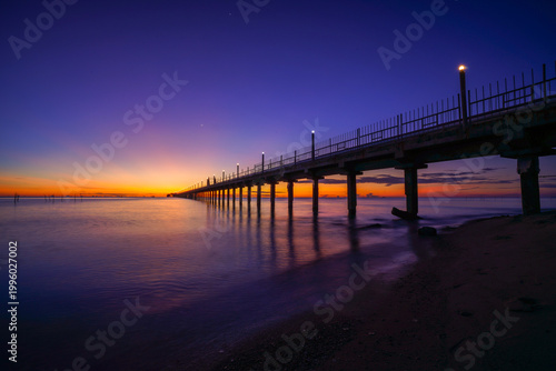 Long pier stretching into the sea during a golden sunset.