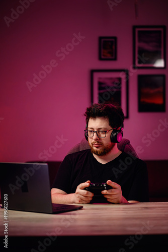 Happy girl gamer taking selfie with smartphone and laptop in pink neon light