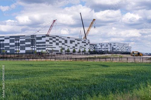 Exterior shot of a new data center building in Hutto, Texas with cranes visible on a partly cloudy day.