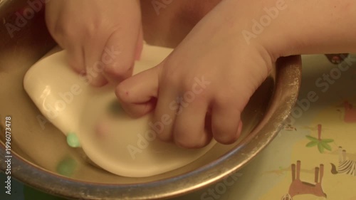 Child hands kneading white slime in metal bowl, sensory squish and stretch, playful tactile exercise, homemade craft therapy, closeup focus on fingers and motion, cleanup empty