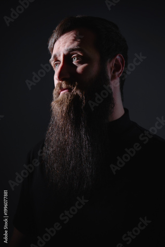 Foto Dramatic portrait of bearded man in dark lighting looking sideways with strong s
