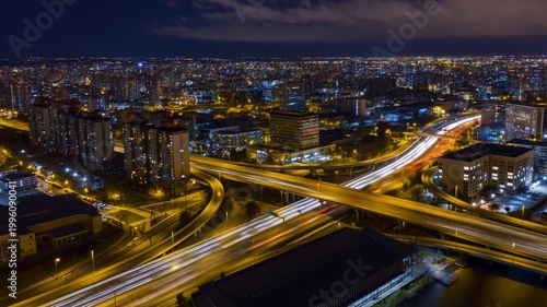 A modern metropolitan city at night, aerial view of illuminated skyscrapers and highway traffic