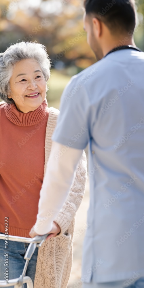 Naklejka premium Elderly woman walking with caregiver outdoors in park