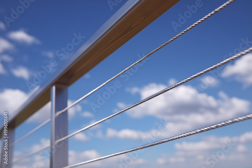 Railing system with thin steel wires overlooking a clear blue sky on a sunny day in a modern building