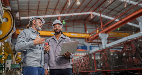 фотографія Industrial engineers wearing safety gear inspecting heavy machinery in a modern factory