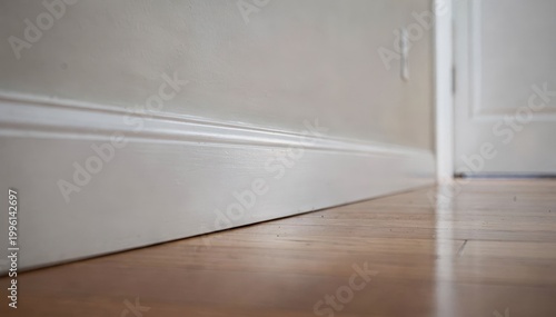 Smartphone lens capturing closeup of unblemished baseboard detail surrounding empty room and blurred fixtures emphasizing meticulous documentation.