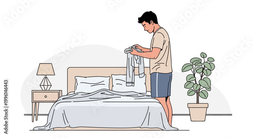 Man tidying up bedroom, folding clothes on bed with nightstand and plant