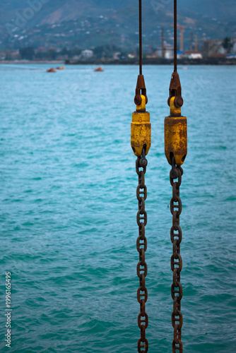 Rusty Industrial Crane Chains Over Blue Sea