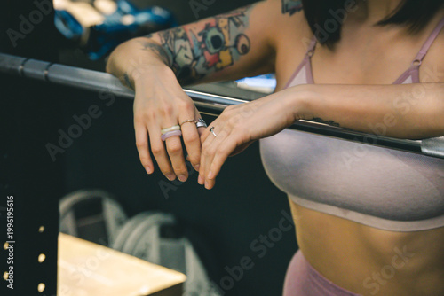 Cropped shot of a fit woman resting on a barbell after training
