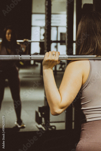 Woman lifting barbell in a gym, focusing on strength training