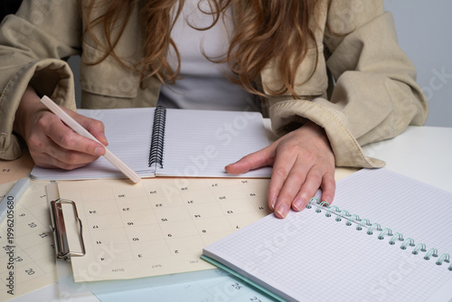 Close-up of woman's hands writing in calendar and marking dates for project planning