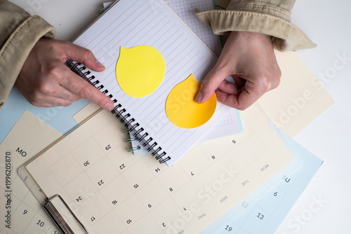 Woman pointing at yellow arrow sticker on calendar for deadline awareness. Business planning concept. 
