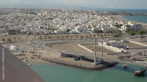 Slow Motion View of Sur Through Lookout Tower Buttresses, Cinematic Framed Panorama of Omani Coastal City