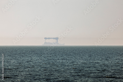 Obraz na plátne Sea view with ship Fata Morgana mirage on distant horizon in haze, atmospheric c