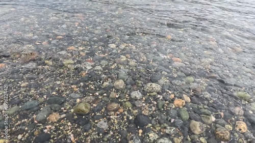 Haines - Alaska - USA - April 21, 2024 - Close up view of a riverbed with clear water flowing over rocks and pebbles. The water creates a smooth surface over the stony texture.