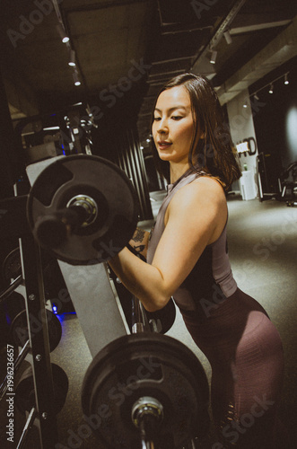 Woman adjusting weights on a barbell in the gym