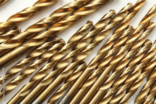 фотографія Collection of golden titanium coated metal drill bits of various sizes arranged diagonally, showcasing metallic texture and industrial pattern