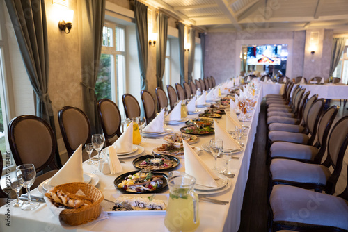Long banquet table with formal setting and appetizers in a restaurant