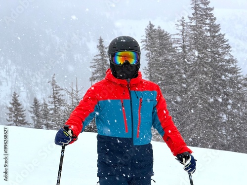 Skier in colorful jacket skiing in snowfall on mountain slope