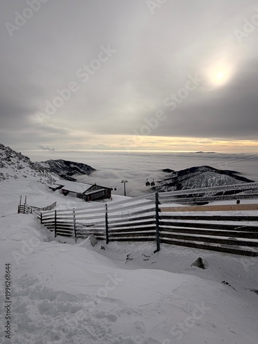 Snowy alpine landscape in Jasna Low Tatras with wooden fence above clouds