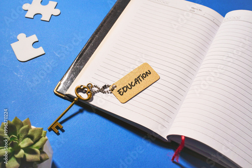 Education is the Key to Success Concept with Vintage Brass Key on Open Notebook and Blue Background