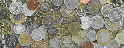 Top view of assorted coins, numerous world currencies together. Shiny metal pieces in mound