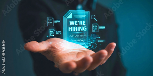 Hand holding a glowing holographic document that reads We're hiring - Join our team, representing digital recruitment and workforce expansion