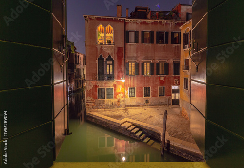 Night view of Venice canal from open window, Italy