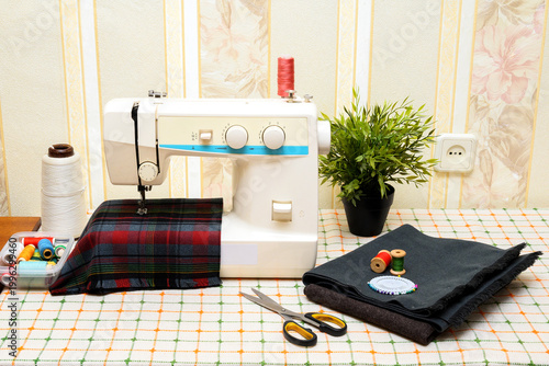 modern sewing machine with accessories on a checkered table