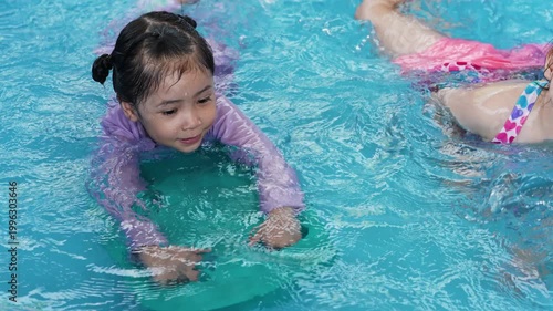slow motion of happy preschool child girl playing together with her sister in outdoor portable swimming pool in backyard at home