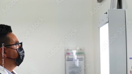 1080p video at 60 fps horizontal of a doctor turning on his negatoscope to review x-rays at a medical appointment
