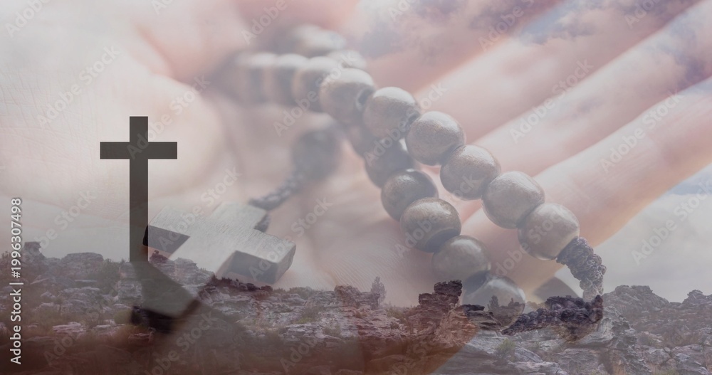 Naklejka premium Holding open palm, adult hand cradling wooden rosary beads over rocky hilltop silhouetted cross