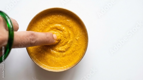 Bright Yellow Turmeric Paste in Bowl with Finger Touch – Natural Skincare and Herbal Beauty Concept