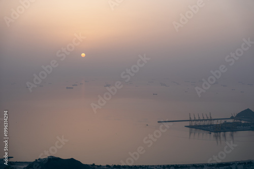 Fotografie Cargo vessels anchored at sunset amid Strait of Hormuz shipping disruption