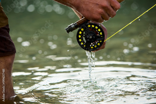 Bilde på lerret Fisherman's hands holding fly fishing reel in river